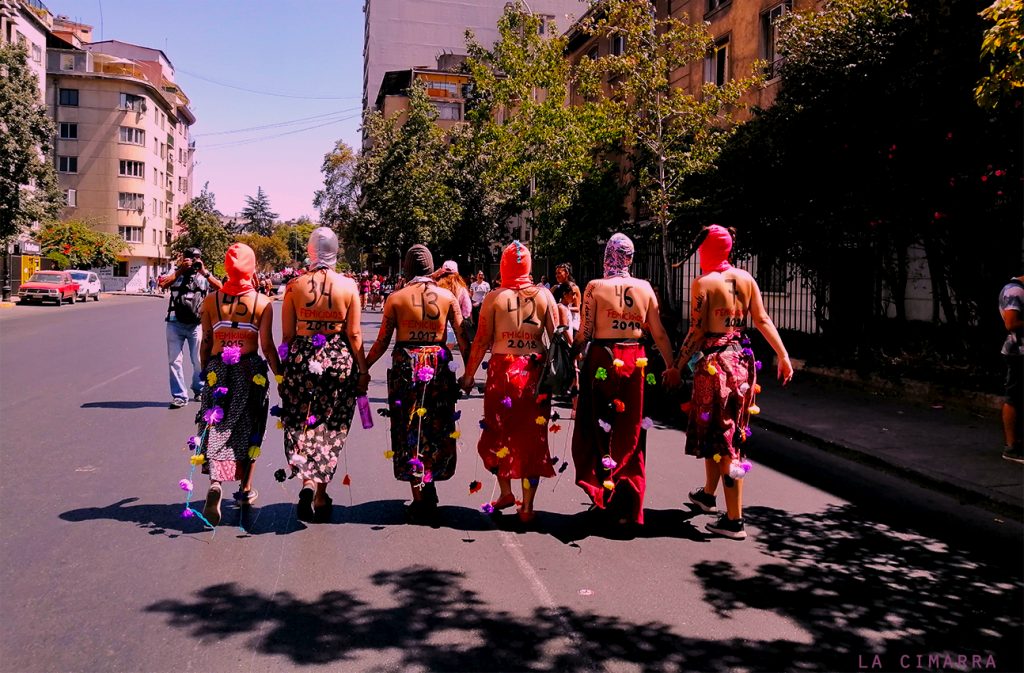 Mujeres marchando con el nro de femicidios por año en Chile, en dirección a la alameda en santiago de Chile